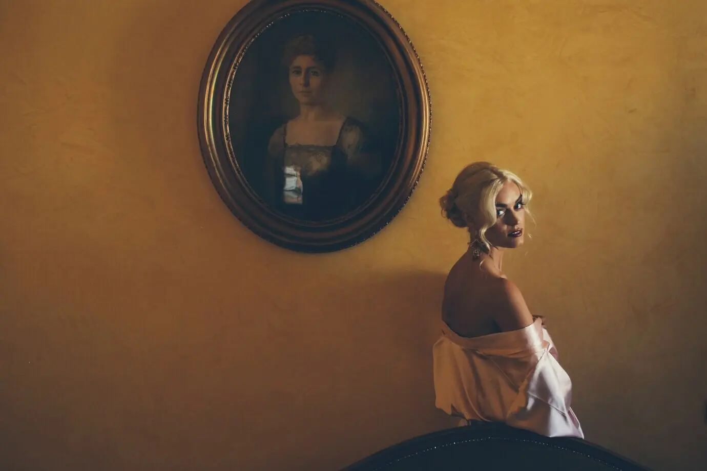 유혹적인 금발 여성이 청동빛 어깨 너머로 시선을 돌리며…