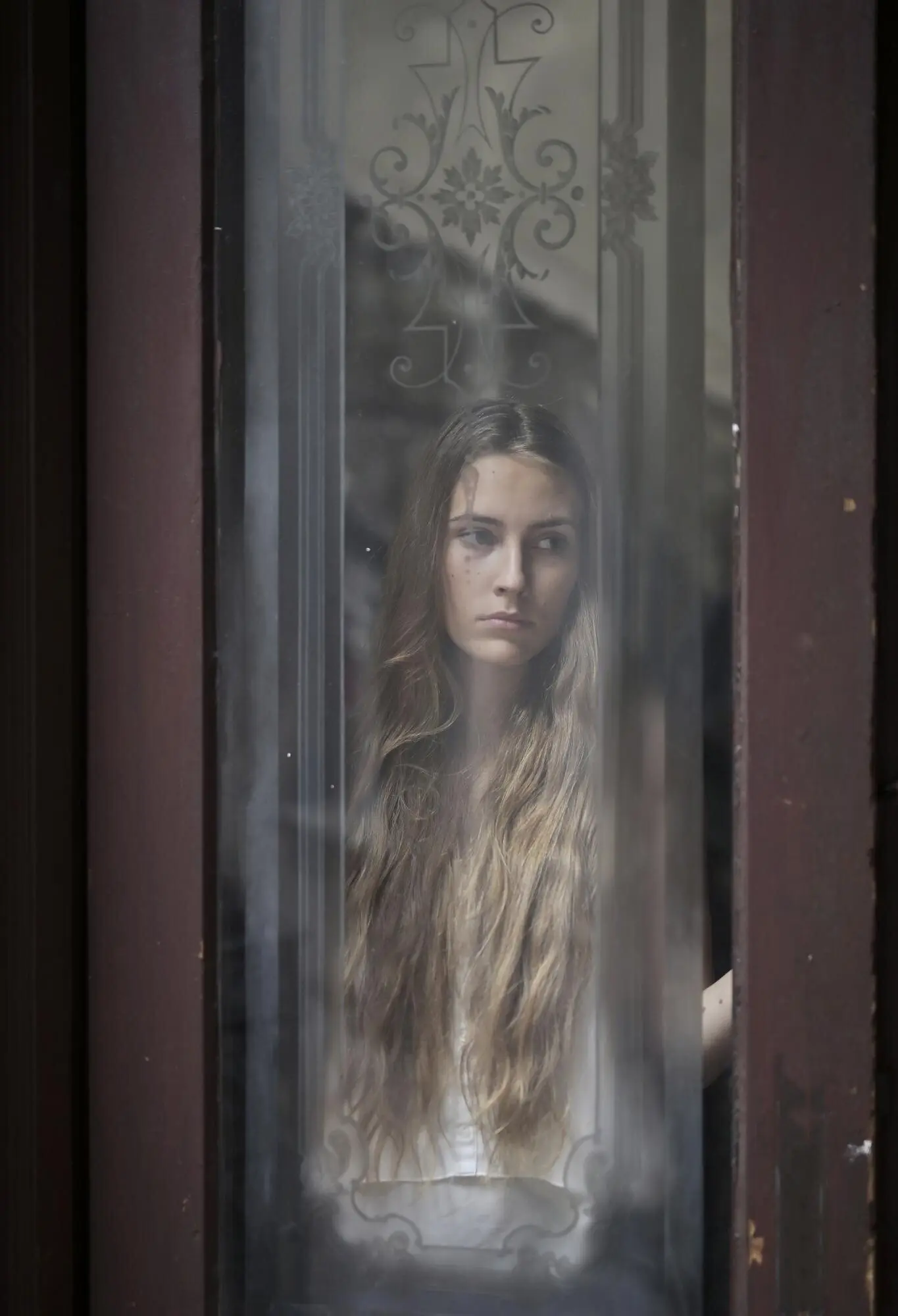 문 유리를 통해 촬영된 젊은 여성