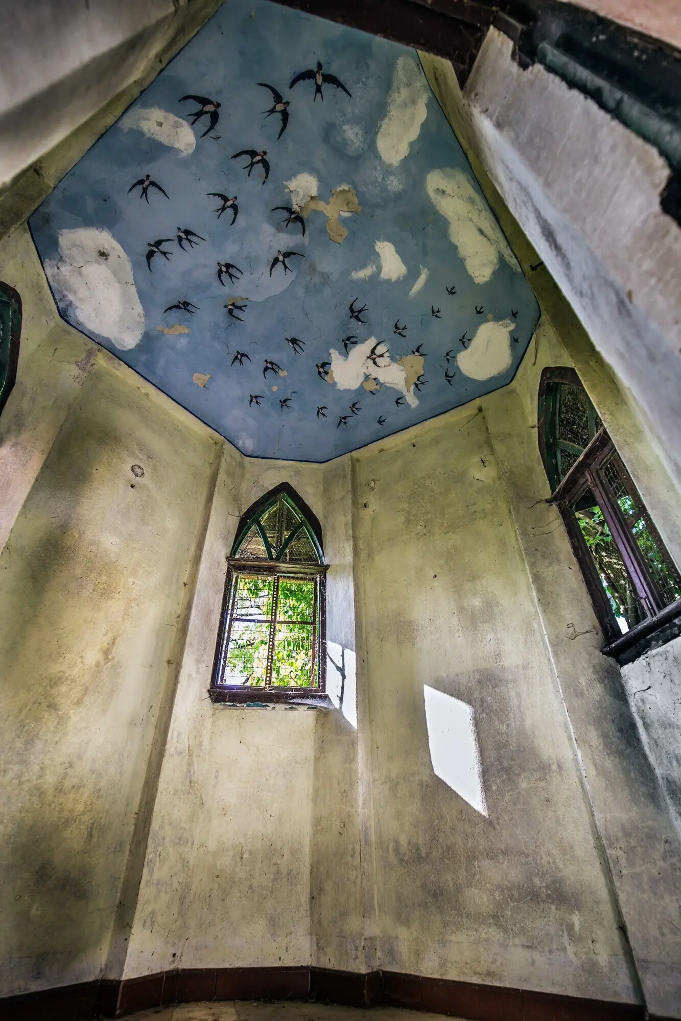 아치형 창문과 천장 그림이 있는 건물 내부를 세로 구도로 촬영한 사진.